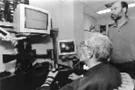 MIT Research Scientist Hermano I. Krebs watches as a patient at the Burke Rehabilitation Hospital uses MIT-Manus, a robotic arm designed to aid in his recovery.