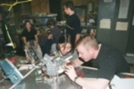 Shannon Cheng (left foreground), a senior in aeronautics and astronautics, and Steve Sell, a consultant for Payload Systems, Inc., troubleshoot a satellite built by students and staff at MIT and about to be tested in NASA's KC-135.