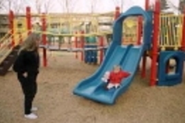 Loni Butera watches her daughter Lara enjoying the slide in the new playground at Westgate.