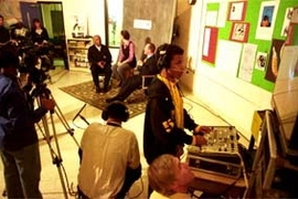 CRLS sophomore Steven Duart, 16, handles some of the studio equipment donated by MIT during an interview show on the school's Channel 98 featuring (background, left to right) City Council member Kenneth Reeves, CRLS teacher Kris Kay and Mayor Anthony Galluccio. In the foreground looking up at the monitor is Thomas P. White, videographer and producer with MIT's Center for Advanced Educational Servi...