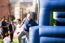 President Charles Vest makes it through the first leg of the obstacle-course relay race as he rushes the baton to his waiting teammates from the Presidential Seals.President Charles Vest makes it through the first leg of the obstacle-course relay race as he rushes the baton to his waiting teammates from the Presidential Seals.