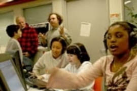 Professor Tod Machover, rear, gestures to one of the Toy Symphony composers, Joshua McLellan, and his dad, Vincent, as MIT UROP student Kay Tye works with composer Kattie Dwyer, 11, of Chelsea. At right, Teyanna Powell-Hughes of Dorchester composes music with a flourish.