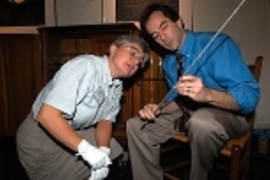 Deborah Douglas, science and technology curator at the MIT Museum, examines one of the thermometers (held by Professor of Mechanical Engineering John H. Lienhard) stored for more than a century in the chest behind them.