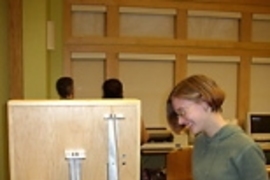 Ellen Cappo shows the column-buckling demonstration. The white bucket on the right transmits identical loads to the three wooden columns. As the bucket's load is increased, the columns buckle, starting with the longest one.