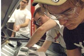 Mechanical engineering students Craig Wildman G, backround and Ryan King '09, center, and Jeremy Kuempel '10 work on putting together the porsche in Sloan Automotive Lab. They are installing a motor controller into the rear trunk compartment of the vehicle.