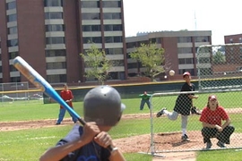 Alex Nickerson is at bat as Jordan Smith pitches to him on Briggs Field at MIT. The two middle school students are participating in MIT's summer Science of Baseball program, which, each morning, teaches them things like how a curve ball works and how to calculate player statistics. In the afternoon, they put their new knowledge to work on the field.