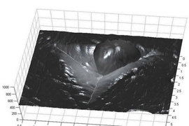 The image shows the imprint left by a nanoindenter in a particle of cement paste. The round blob at the top center is actually an extremely fine piece of dust on the surface.