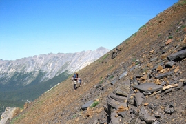 Francis Macdonald pauses to collect a rock on the steep scree at the bottom of the section of rocks that contain the microfossils. Phoebe Cohen's rock hammer sits in the foreground. 