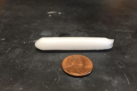 A paraffin wax capsule developed by researchers at MIT is shown next to a penny.