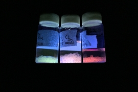 Luminescent materials produced by the MIT team are shown under ultraviolet light, emitting different colors of light that can be modified by their environmental conditions.