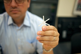 The star-shaped drug delivery device, held here by Giovanni Traverso, a Koch Institute research affiliate, can be folded inward and encased in a smooth capsule. Once ingested, the device delivers a full drug payload gradually over weeks or even months. 
