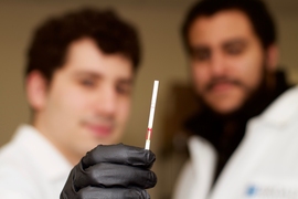 Co-first authors Jonathan Gootenberg (left) and Omar Abudayyeh (right) holding a paper strip that displays a positive SHERLOCK readout. 
