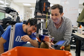 Elliott Donlon (left) and Francois Hogan (right) work with the robotic system that may one day lend a hand with this household chore, as well as assist in other picking and sorting tasks, from organizing products in a warehouse to clearing debris from a disaster zone. 
