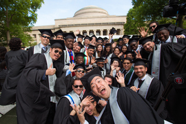 Crowd of graduates in caps and gowns smiling and waving