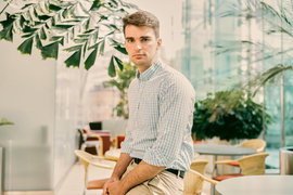 Keith Murray, seated, looks at the camera, with windows and potted plants in the background