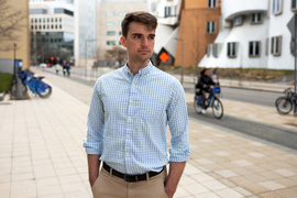 Keith Murray stands outside on MIT's campus, with cyclists passing by in the background