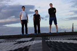 3 people stand outside smiling. 