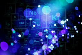 dots of light with different shades of blue in various levels of focus over a black background with outlines of elements in the periodic table.