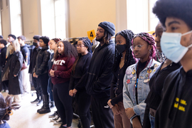 About 20 MIT community members stand while listening to the ceremony.