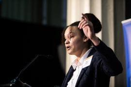 Nicole Harris speaks at podium and gestures with one hand raised.