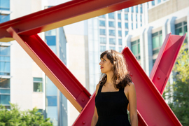 Jaye stands in Hockfield Court with the red sculpture, Mark di Suvero’s Aesop’s Fables, II, 2005.