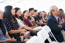 Smiling audience members watch the show under a white tent.