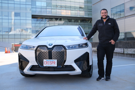 Omar Abudayyeh smiles next to his white BMW with the license plate, “CRISPR.”