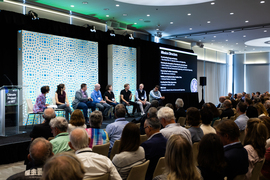 A panel on stage taking questions from a journalist.