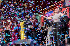 Tons of confetti falls as Peko Hosoi smiles and people mingle on stage.