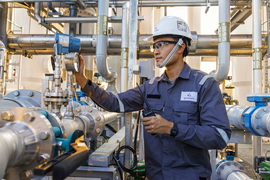 Worker in protective gear checks a valve inside an industrial plant