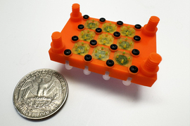 The 3D-printed device has a 3x3 array of cone-shaped emitters, and is next to a quarter showing that it’s about twice the size.