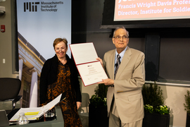 Mary Fuller and John Joannopoulos, who holds paper award, in front of class auditorium.