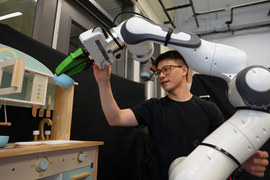 Felix Yanwei Wang working with a robotic arm that is holding a bowl